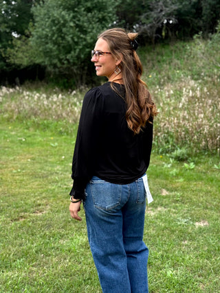 A lady wearing a black top with smocking detail.