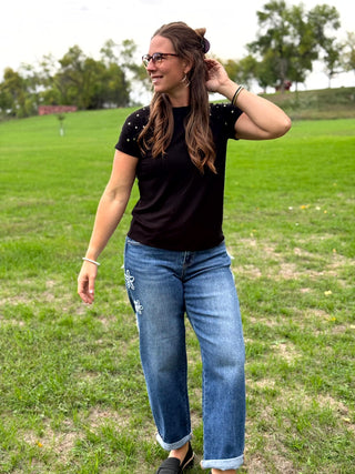 Lady wearing black ribbed top with gold studs on sleeves.