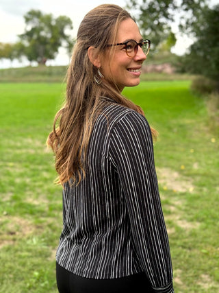 A lady wearing a black and white pin stripe blouse with a scarf detail.