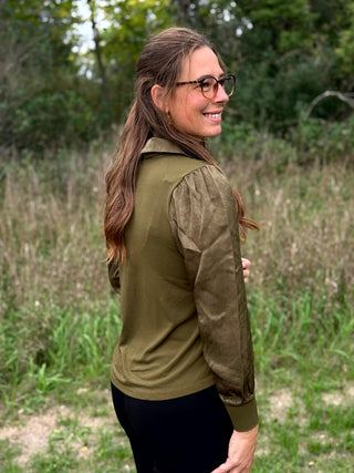 A lady wearing a olive green top with a scarf detail.
