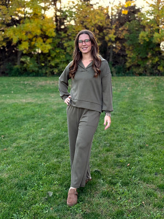 Model wearing an olive green lounge set with a collared V-neck top and matching wide-leg pants.
