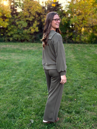 Full-length side-back view of an olive green matching set showing the pullover’s banded hem and wide-leg pants.⠋

