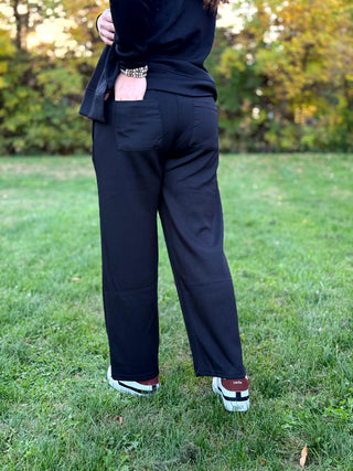 Back view of black wide-leg lounge pants with two patch pockets, styled with a matching long-sleeve top.