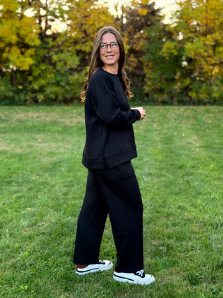 Side view of model wearing a relaxed black lounge set with a side-slit top and wide-leg pants.