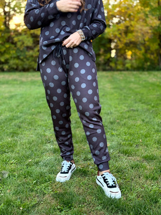 Model wearing dark charcoal joggers with large gray polka dots, a drawstring waist, and cuffed ankles, paired with a matching top.