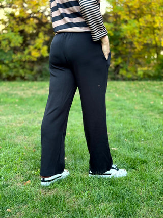 Back view of black wide-leg pants showing the elastic waistband and relaxed fit.