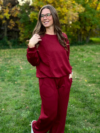 Front angled view of a burgundy matching set with a relaxed long-sleeve top and wide-leg pocketed pants.