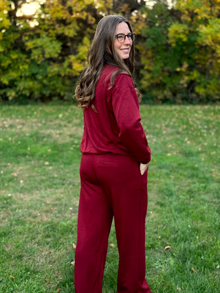 Rear three-quarter view of a burgundy matching set with wide-leg pants and a back welt pocket.