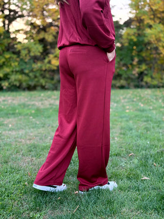 Rear side view of burgundy wide-leg pants showing a back welt pocket and relaxed fit.