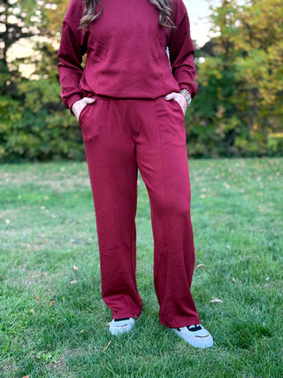 Front view of burgundy wide-leg pants with side pockets, styled with a matching long-sleeve top.