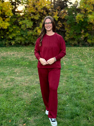 "Woman walking toward the camera in a burgundy sweatshirt and wide-leg pants set."