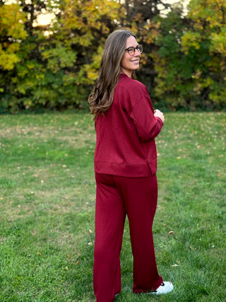 Back view of burgundy matching set showing the top’s wide hem and side slit with relaxed wide-leg pants.