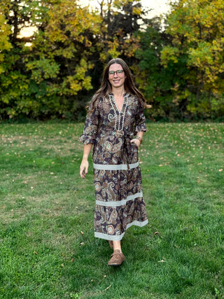 A lady wearing a midi brown tone paisley dress.