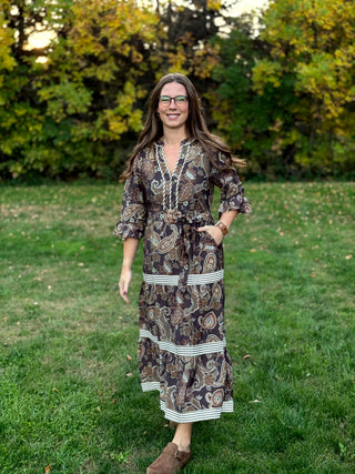 A lady wearing a midi brown tone paisley dress.