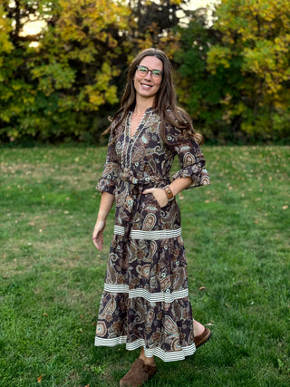 A lady wearing a midi brown tone paisley dress.
