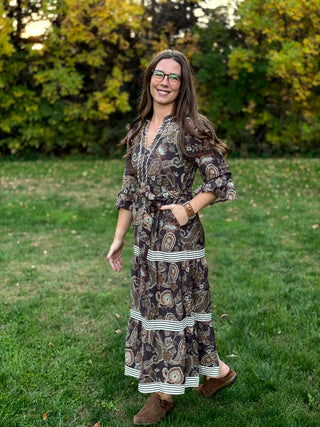 A lady wearing a midi brown tone paisley dress.