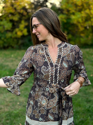 A lady wearing a midi brown tone paisley dress.