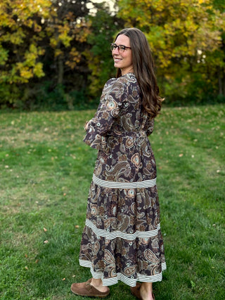 A lady wearing a midi brown tone paisley dress.