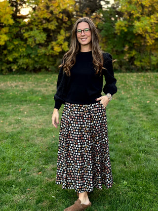 A lady wearing a polka dotted brown tone skirt.