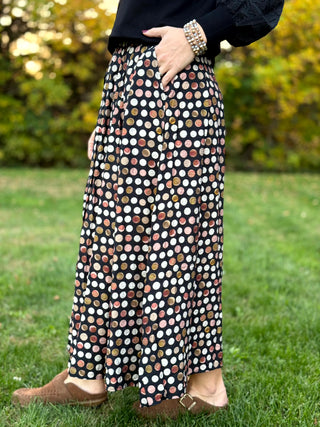 A lady wearing a polka dotted brown tone skirt.