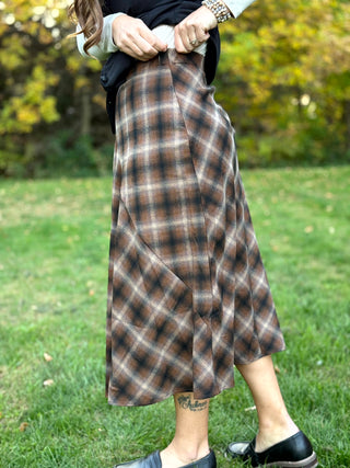 A lady wearing a brown plaid maxi skirt.