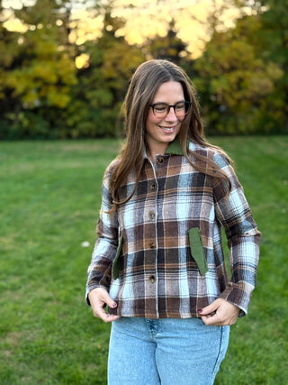 A lady wearing a brown plaid jacket with green corduroy collar and pockets.