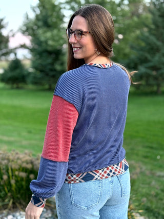 Make a statement in this red and navy mixed-media sweater. Featuring plaid, stripes, and cozy waffle knit, it's the ultimate blend of style and comfort. Shop now!