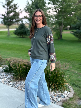 Elevate your everyday style with this uniquely crafted olive Henley featuring eye-catching plaid patchwork sleeves. Its ultra-soft fabric and relaxed fit provide the perfect blend of rustic charm and modern comfort.