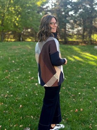 Full-length rear-side view of the colorblock sweater styled with dark wide-leg jeans and sneakers.