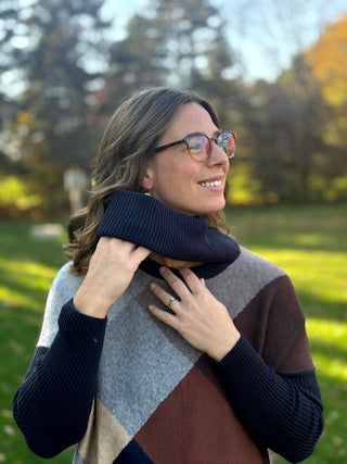 Model wearing the colorblock sweater while holding a matching navy ribbed cowl around her neck.