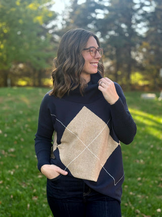 Front view of the navy and beige argyle sweater with a draped cowl neck and relaxed fit.