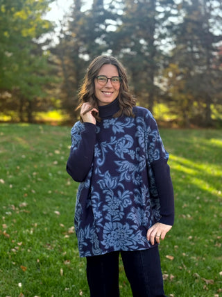 Front view of a model wearing a relaxed navy floral tunic with a ribbed turtleneck and long navy sleeves.