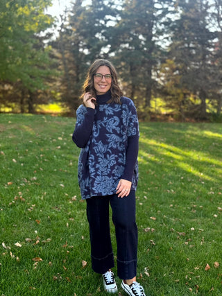 Full-length view of a model wearing a navy floral tunic with dark wide-leg cropped jeans and sneakers.