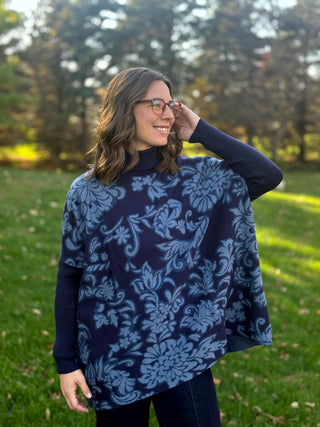 Front view of a navy and slate-blue floral tunic with a ribbed turtleneck, fitted sleeves, and flowing hem.