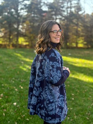 Close-up back view of a navy floral tunic showing its draped silhouette and ribbed navy sleeves.