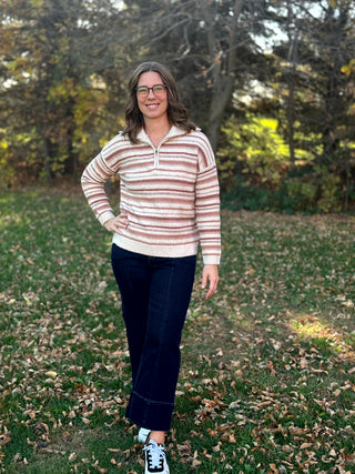Full-length view of a model wearing a cream striped quarter-zip sweater with dark wide-leg jeans and sneakers.