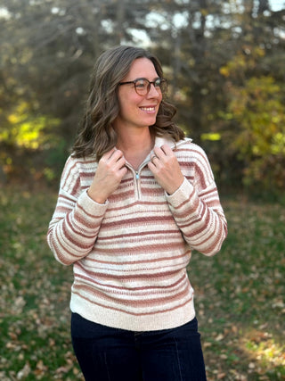 Front view of a cream, pink, and taupe striped sweater with a quarter-zip collar and ribbed trim.