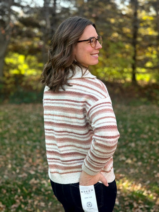 Close-up back view of a cream striped sweater showing textured knit, dropped shoulders, and ribbed cuffs.