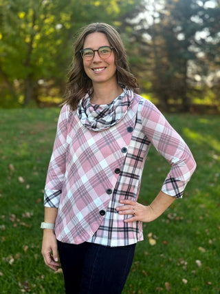 Front view of the pink plaid top, showing black side buttons, contrasting plaid panels, and a curved hem.