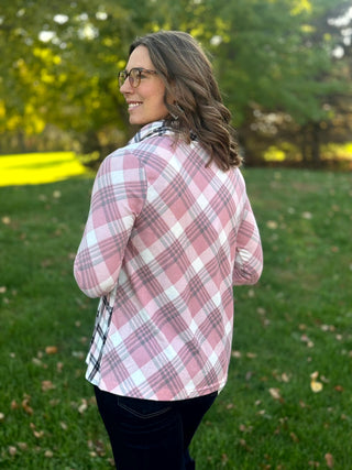 Back view of a model wearing a pink, white, and gray plaid top with three-quarter sleeves and dark jeans.