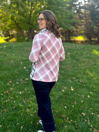 Back view of a model wearing a pink, white, and gray plaid top with three-quarter sleeves and dark jeans.