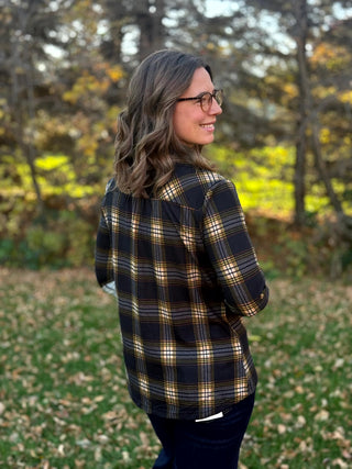 Close-up back view of a black, tan, and gray plaid shirt, showing the shoulder yoke and relaxed fit.