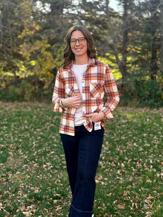 Full-length front view of a model wearing a cream plaid shirt open over a white tee with dark wide-leg jeans.