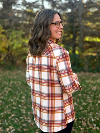 Close-up back view of a cream plaid shirt with rust and tan stripes, a back yoke, and curved hem.