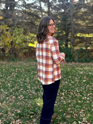 Model wearing a cream, rust, and tan plaid shirt with dark jeans, shown from the back and side.