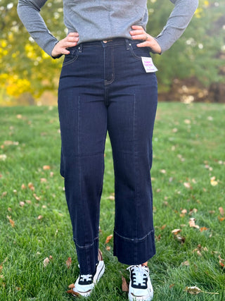Front view of dark-wash cropped wide-leg jeans with contrast stitching and wide stitched hems.