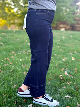 Side view of dark-wash cropped jeans showing the hip pocket, relaxed leg, and wide hem.