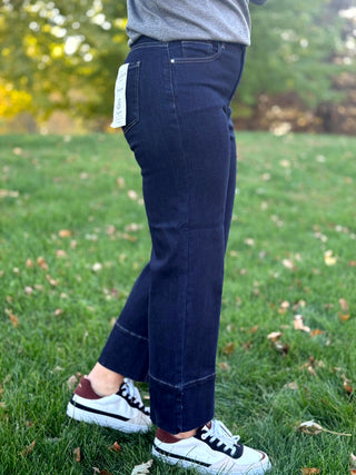Angled side view of dark-wash wide-leg jeans showing the cropped length and contrast-stitched hems.