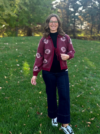 Full-length front view of a burgundy floral cardigan styled with dark wide-leg jeans and white sneakers.