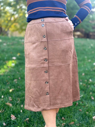 Front view of a camel-brown midi skirt with button-front closure, horizontal panel seams, and side pockets.